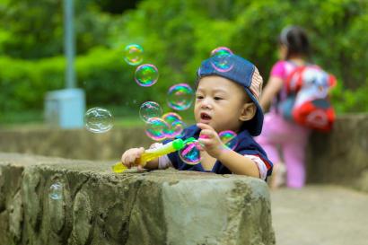 Little boy blowing bubbles in a park